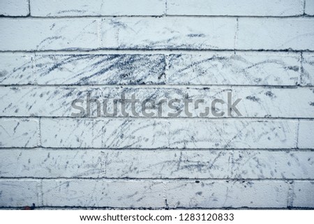 White brick wall texture in parking lot with black scuff marks.  Royalty-Free Stock Photo #1283120833