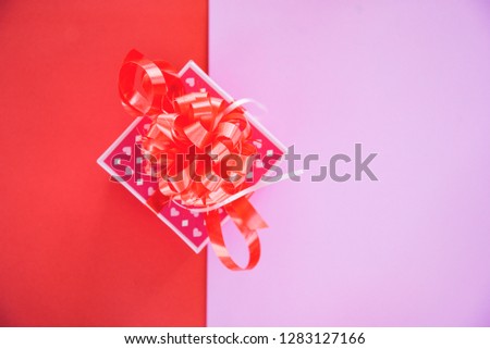 Pink gift box ribbon bow for gift to Merry Christmas Holiday Happy new year or Valentines day on red half pink background 