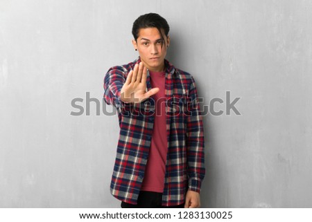 Man over grunge wall making stop gesture denying a situation that thinks wrong