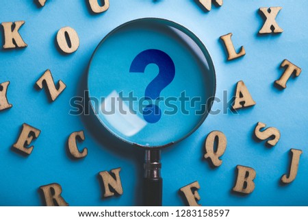 Question Mark Magnifying with wooden alphabets around on the blue background.