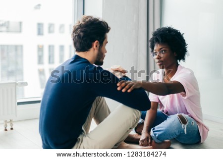 People, lifestyle and relaxation concept, two young multi-ethnic lovers sit opposite each other with joined hands, feeling spiritual unity and love