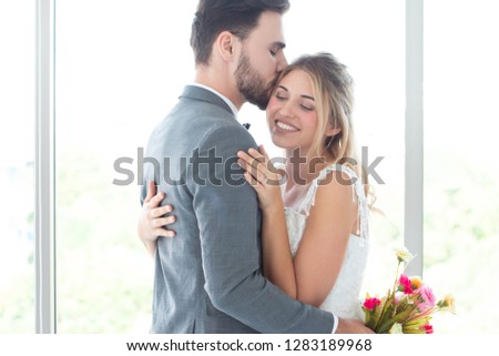 a couple love standing in wedding studio with a man surprise give bouquet of flowers to his bride