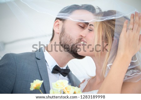 Portrait picture of couple love kissing on face together in wedding studio with wear suit and bride dress