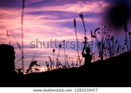 Children holding christian cross overhead with light sunset and behind tall grass,christian concept.