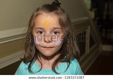 Girl with face painting makeup of 2 ducks and a bright sun at a party event.