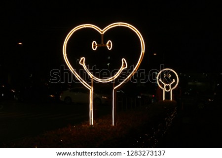Heart shaped smiling face neon light sign on the street side at night