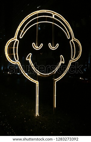 Vertical image of smiling Happy face shaped neon light sign on the street side at night