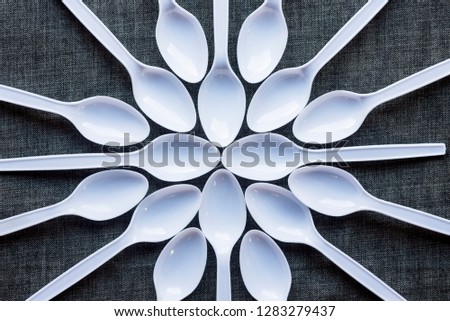 
White plastic spoon that is placed on a dark fabric