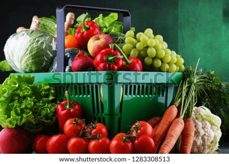 Fresh organic fruits and vegetables in plastic shopping basket.