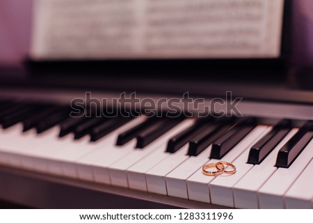 Two golden wedding rings laying on the piano keys