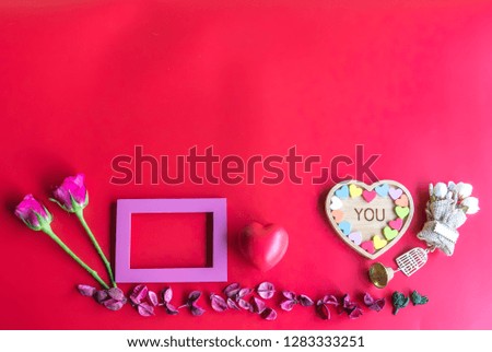 Valentine  concept  setting  with  rose,wooden  picture  frame  and  heart  on  red  background
