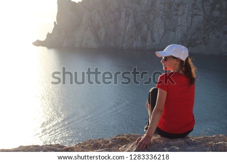 Young, beautiful and slim tourist posing on the rocks on the Black Sea coast in Crimea, Russia. Active girl in search of adventure