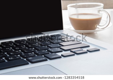 1 cup of coffee beside the laptop is placed on a white desk.