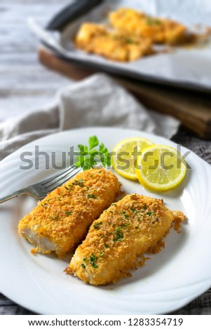 Low carb crispy baked cod, with almond flour, parmesan cheese, butter, paprika, parsley, lemon, garlic. Rustic background