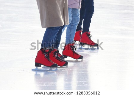 feet of different people skating on the ice rink
