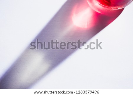 Glass bottle close-up with colorful shadows and flares on a white background. Geometric shapes in photography concept. Direct sunlight flat lay with copy space. Royalty-Free Stock Photo #1283379496