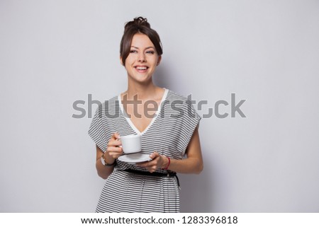 Portrait of a happy young business woman holding cup of coffee isolated over white background