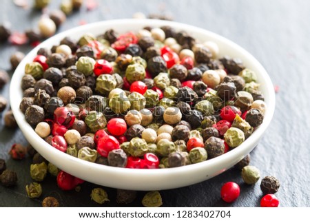 Different colorful spice white black green red pepper closeup background