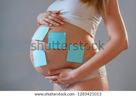 Pregnant woman with paper stickers on tummy, closeup. Concept of choosing baby name. Pregnant woman with stick notes on her belly . 