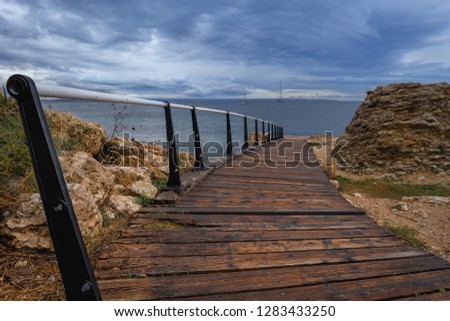 Steep wooden staircase with iron railing leads to the coast in the Greek city of Chersonissos