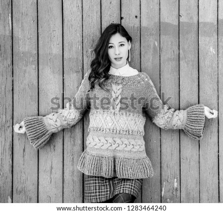 The fashionable girl poses in a knitted pullover outdoors