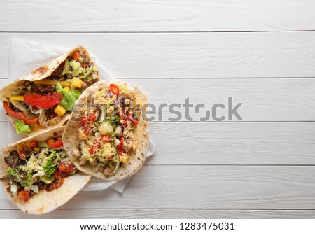Tasty tacos on white wooden table