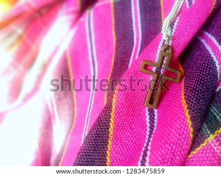 Close up view of Jesus christian crucifix cross on colorful local cloth, God loving concept picture with selective focus