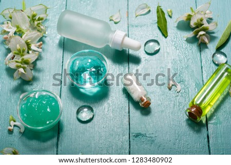 shampoo, shower gel, essential oil, pipette and clary on blue wood table
