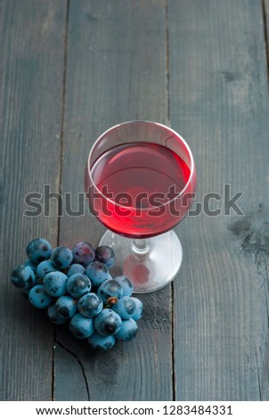 glass of red wine and grapes on black wood table background