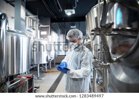 Professional technologist using tablet in production plant checking productivity and quality. Royalty-Free Stock Photo #1283489497