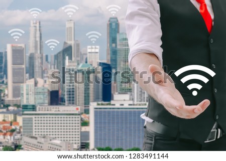Internet technology and networking concept, Businessman hand shows the wifi symbol and wifi sign and high building in the city background