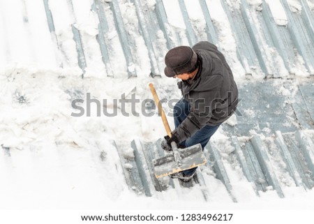 Man clears snow with a wooden shovel, street winter snow removal.
