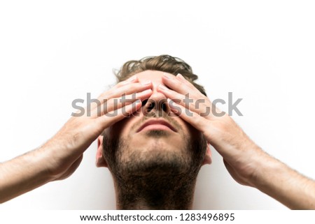 A portrait of a man his eyes closed by his hands against the white background Royalty-Free Stock Photo #1283496895