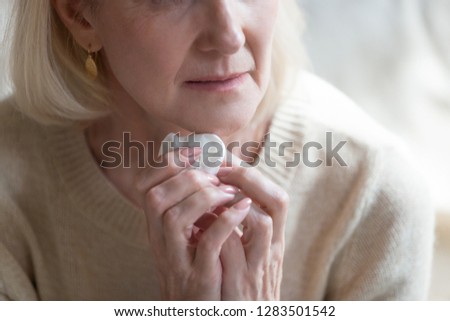 Cropped close up image of unhappy unhealthy middle aged blond woman crying holding in hands handkerchief, mature mature caucasian female sixty years feeling badly she puzzled with piled up problems Royalty-Free Stock Photo #1283501542