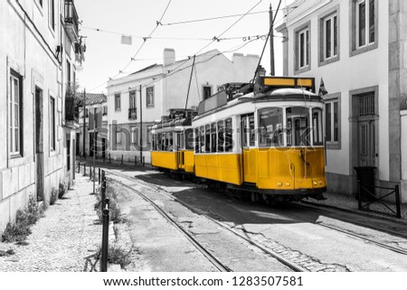 Yellow tram on old streets of Lisbon, Alfama, Portugal, popular touristic attraction and destination. Black and white picture with a coloured tram.