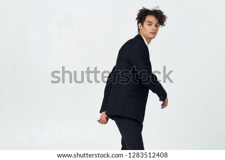 Curly guy in a suit looks into the camera side view                       