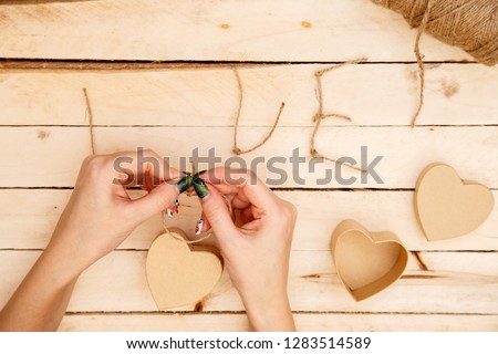 Concept for love stories and for Valentine's Day. Female hands make boxes in the form of a heart and the inscription "love" from a rope. View from above.