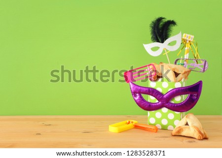 Purim celebration concept (jewish carnival holiday) over wooden table and green background