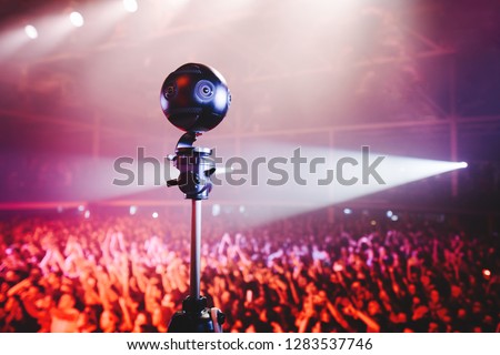 Professional 360 camera at music concert on a tripod recording performance on video.
silhouettes of crowd in front of bright stage lights. Royalty-Free Stock Photo #1283537746