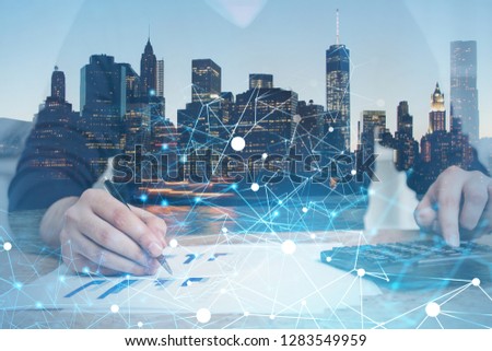 Unrecognizable businessman working in office with calculator over cityscape background with glowing network interface. Toned image double exposure