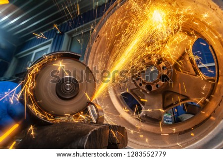 A close-up of a car mechanic using a metal grinder to cut a car bearing  in an auto repair shop, bright flashes flying in different directions, in the background tools for an auto repair