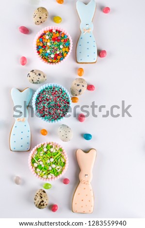 Easter spring decorative composition. Making homemade sugar cookies.  Biscuit in the shape of  a  funny  rabbit , tools necessary to make gingerbread pastry, colored sprinkles.