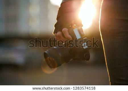 Closeup shot of a man  in gloves holding dslr camera against the sun light. Empty space