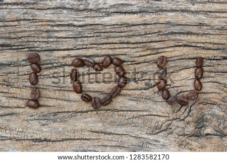 coffee beans used to spell "I love you" text on wood background.
