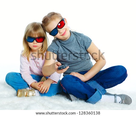 Studio shot of two girls in 3d glasses with control panel watching TV. Isolated white background