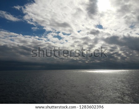 Blue sky with cumulus clouds separated from the sun, floating above the ocean - perfect for background. Blue pastel heaven in soft focus. Simple shot of peaceful and beautiful nature.