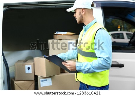 Young courier checking amount of parcels in delivery van, outdoors