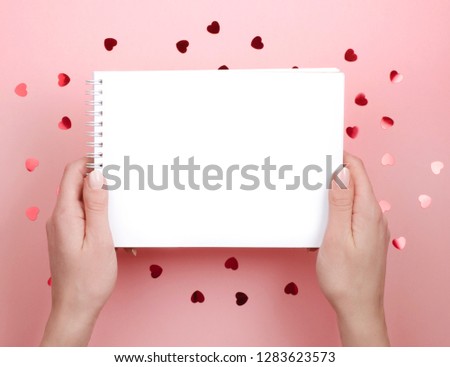 The white notebook in his hands. Pink background with hearts. Romance