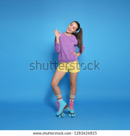 Full length portrait of young woman with roller skates on color background