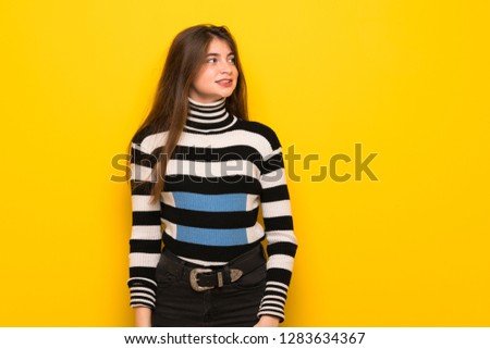 Young woman over yellow wall is a little bit nervous and scared pressing the teeth